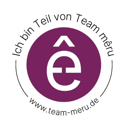 Ein digitaler Stempelabdruck. In der Mitte ist ein Lila ausgefüllter Kreis mit einem weißen ê darin. Über dem Kreis steht "Ich bin Teil von Team mêru". Darunter steht "www.team-meru.de"